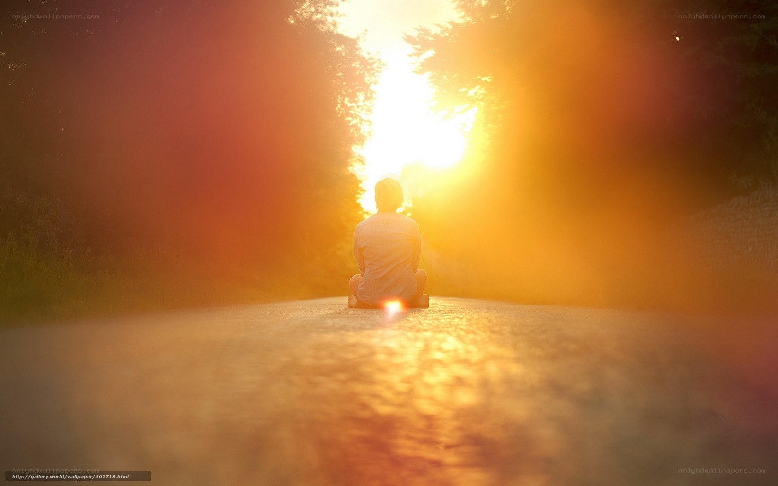 Person sitting on road at sunset
