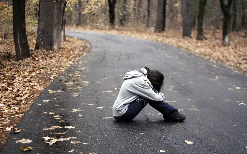 person sitting on road in forest