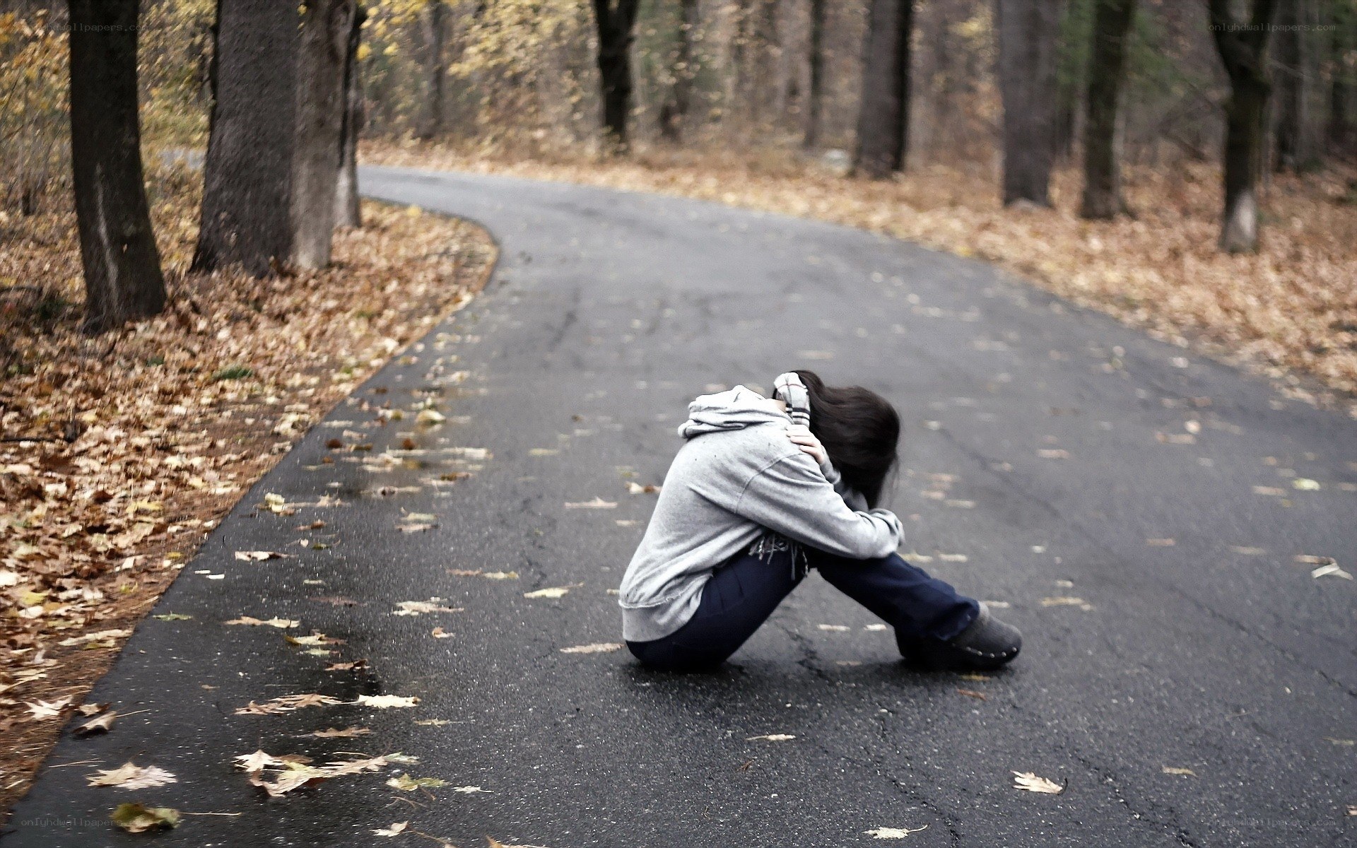 person sitting on road in forest