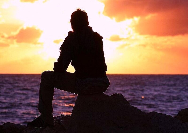 person sitting on rock at sunset