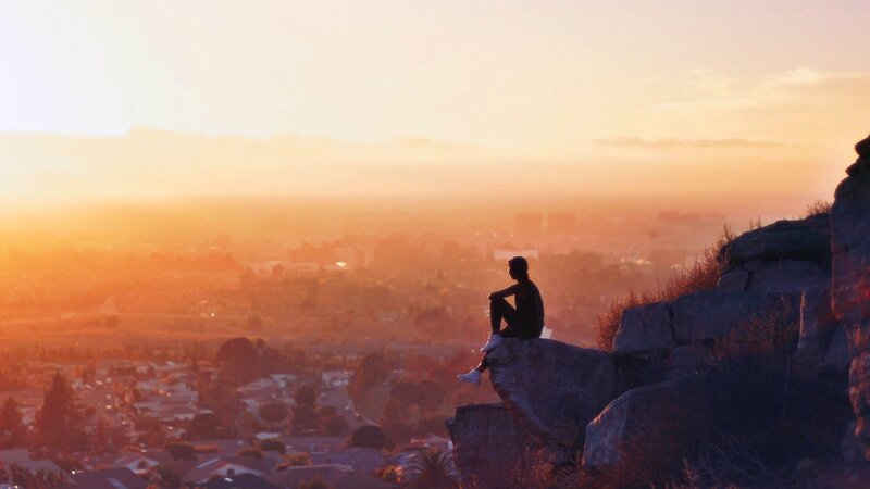 Person Sitting on Rock — Orange