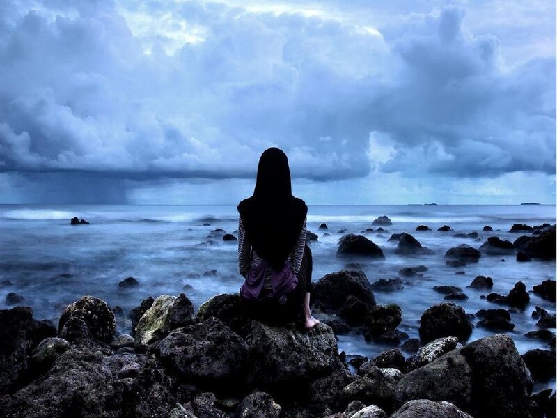 Person sitting on rocks by the sea