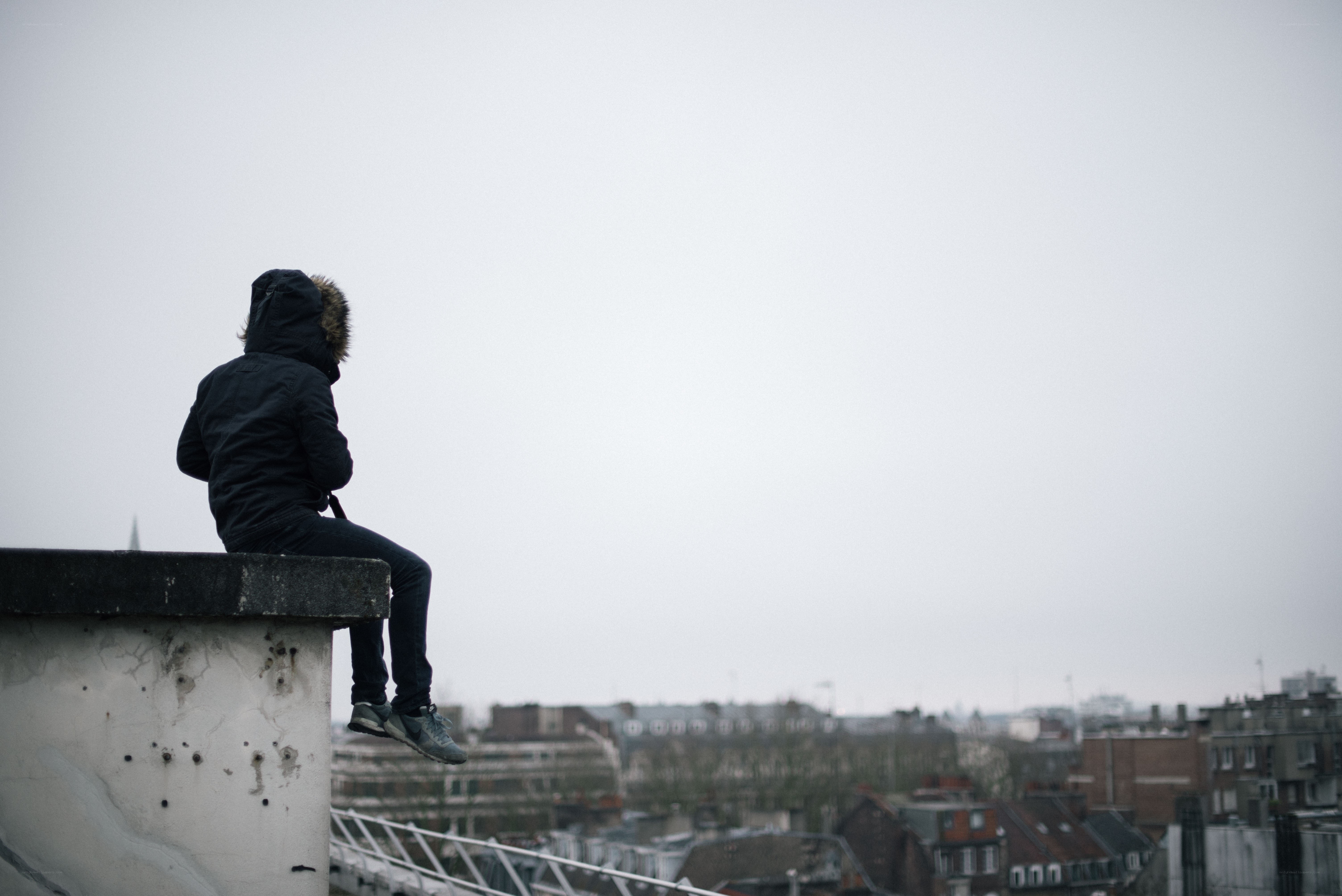 person sitting on rooftop edge