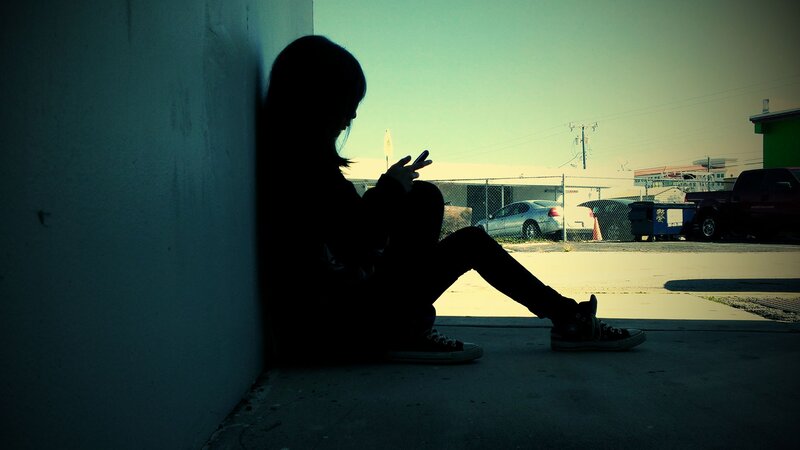 person sitting on sidewalk