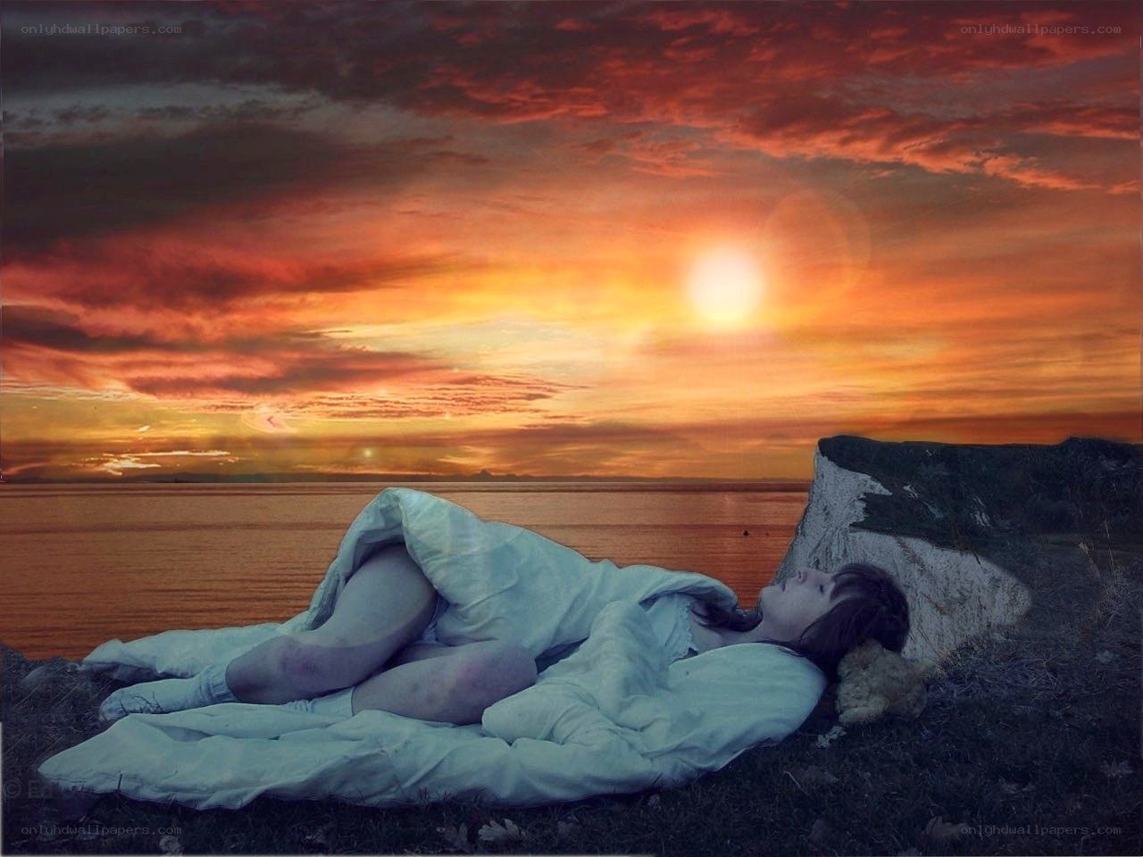 Person sleeping on cliff at sunset