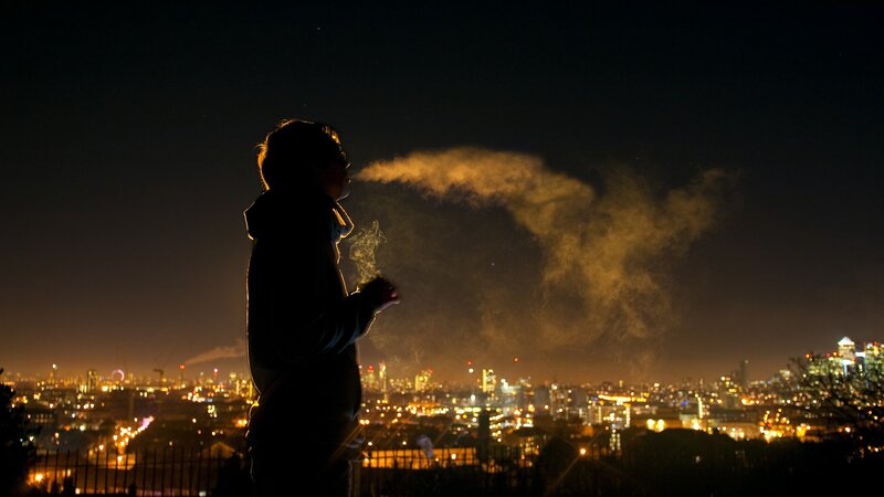 Person smoking at night with city view