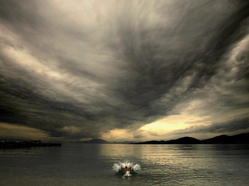 Person splashing in water under stormy sky