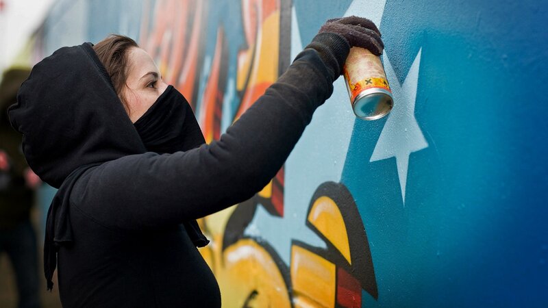Person Spray Painting Wall — Blue