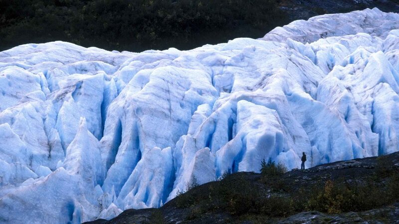 person standing before a glacier