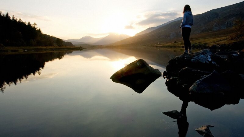 person standing by a lake at sunset