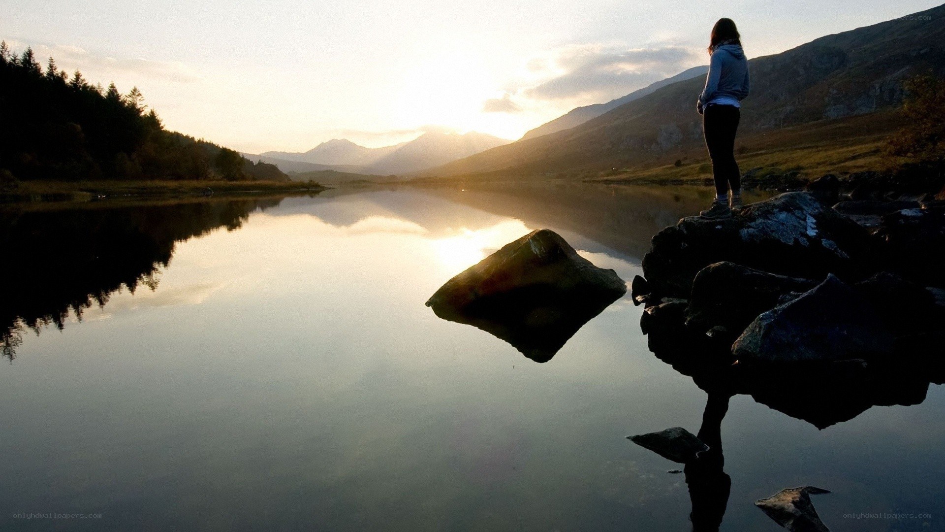 person standing by a lake at sunset