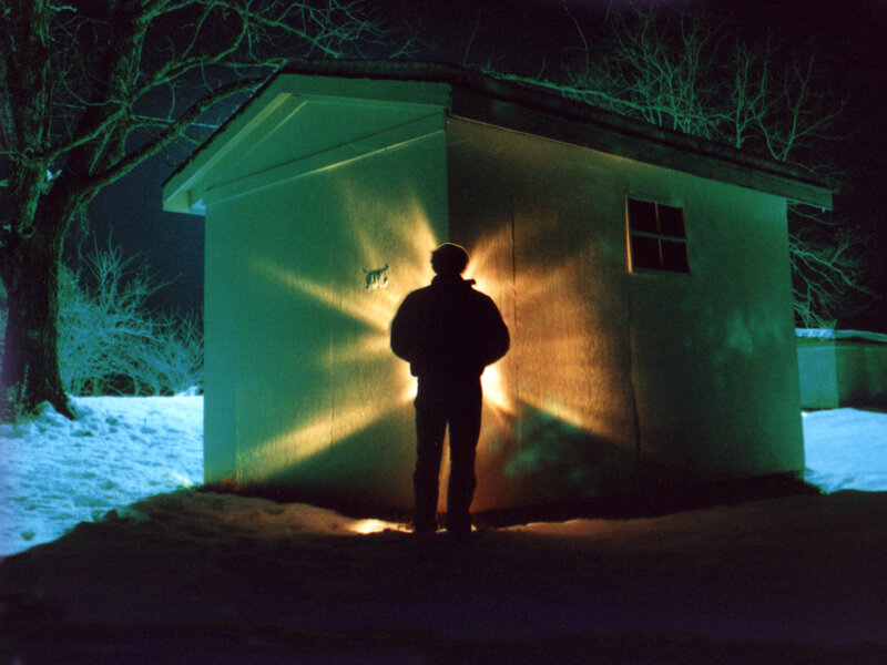 Person standing by shed at night