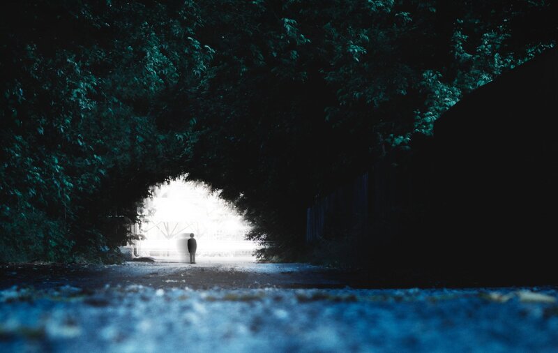 person standing in tunnel of light