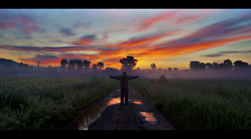 Person standing on path at sunrise