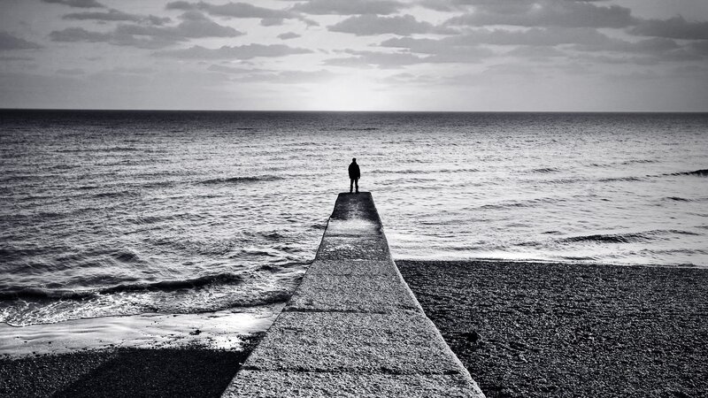 person standing on pier at sea