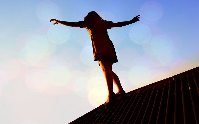 person standing on roof at sunset