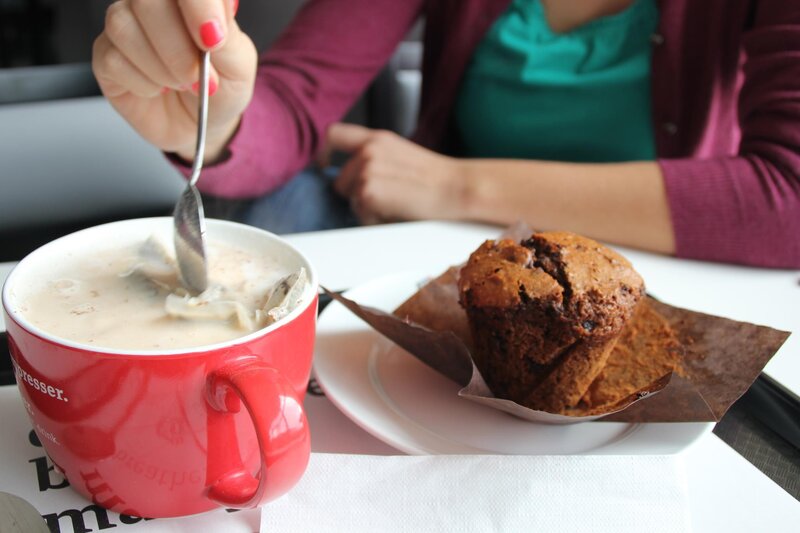 person stirring coffee with muffin