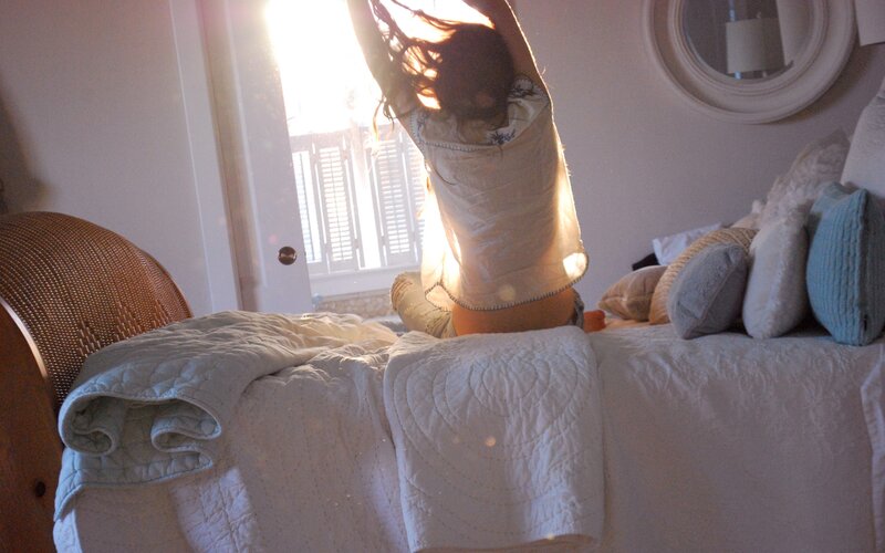 person stretching in bed at sunrise