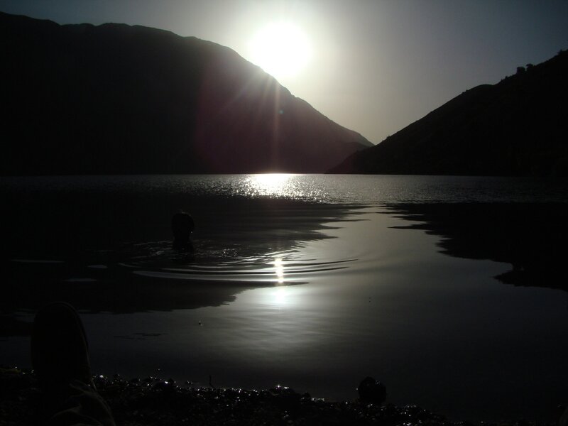 person swimming in lake at sunset
