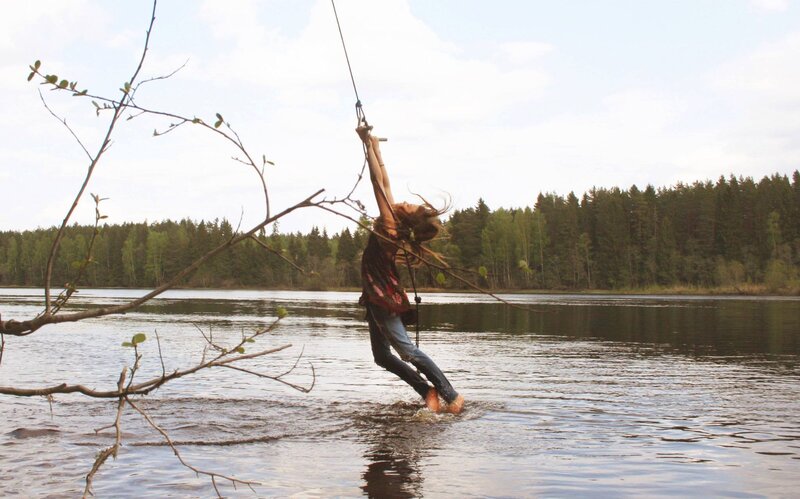 person swinging on rope over water