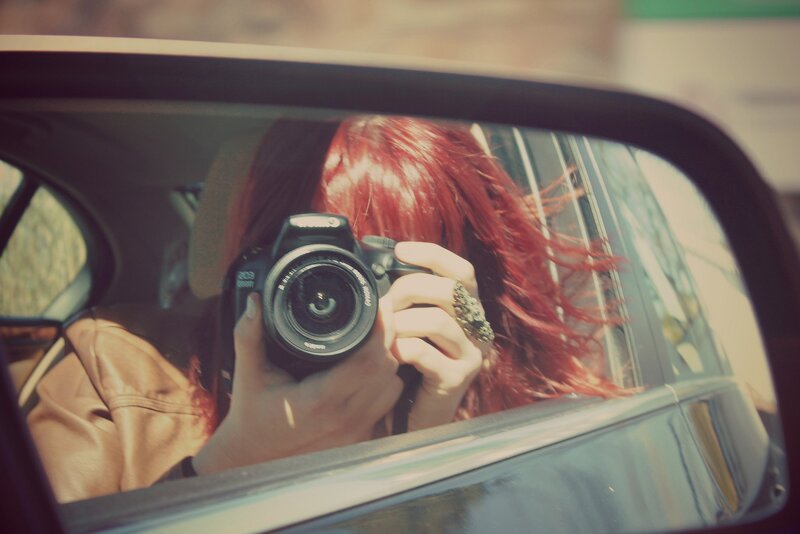 Person taking photo in car mirror
