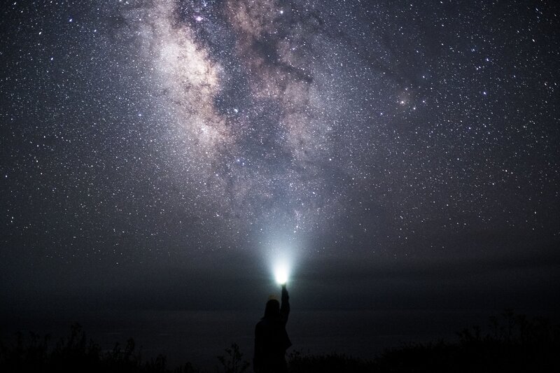 Person under starry sky with flashlight