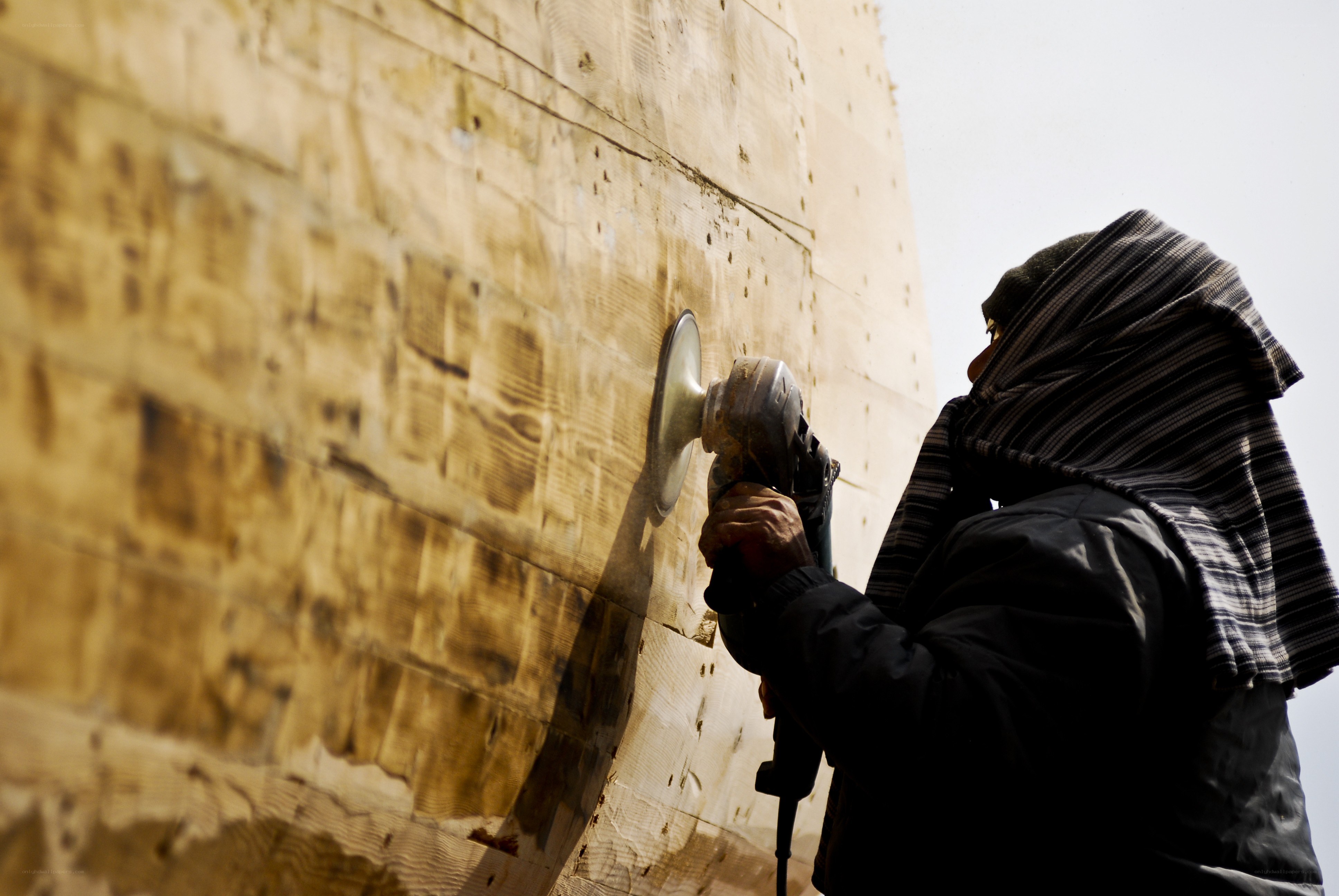 Person using grinder on wooden wall