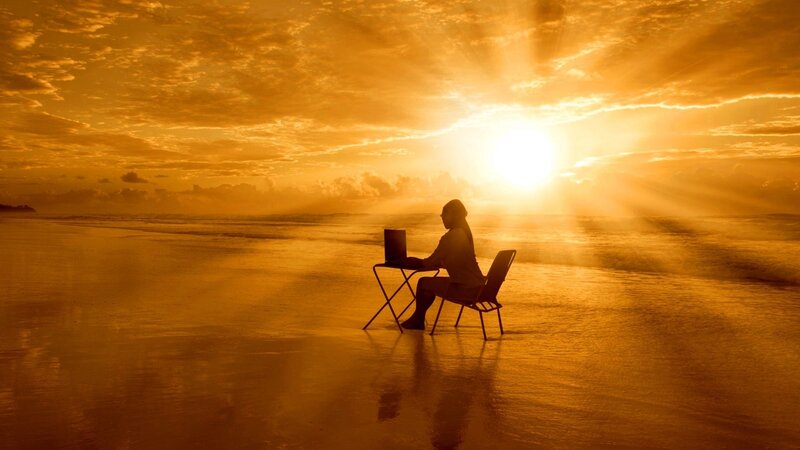 Person Using Laptop on Beach — Orange