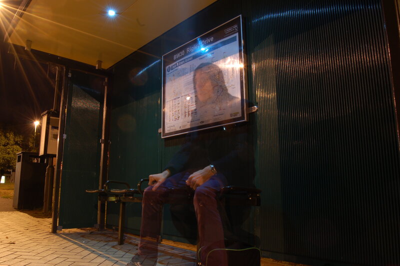 Person waiting at bus stop at night