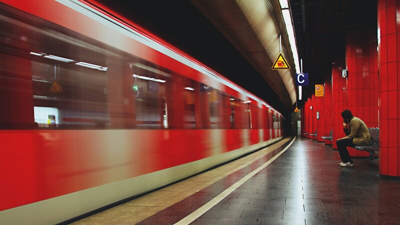 Person Waiting on Train Platform — Red, Dramatic
