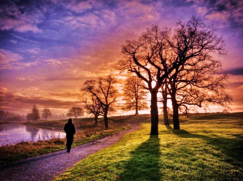 Person walking at sunset by a river