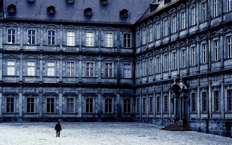 Person Walking in Courtyard — Blue