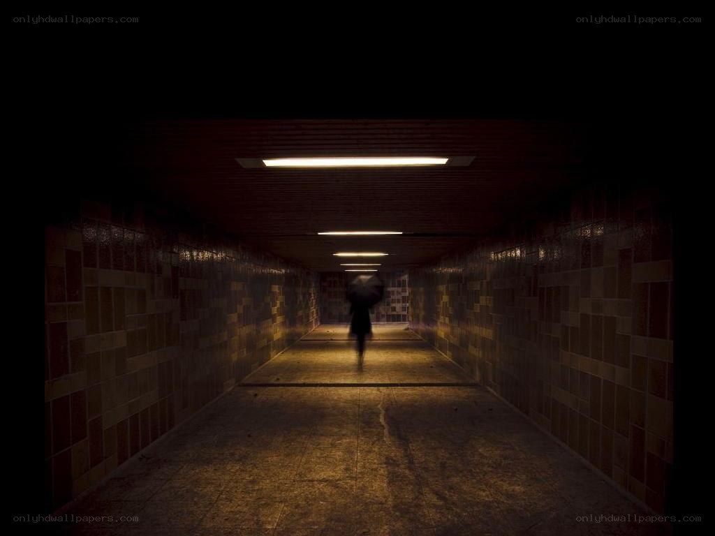 person walking in dark tunnel
