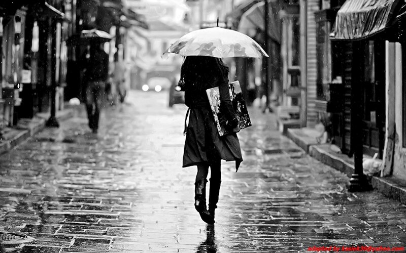 person walking in rain with umbrella