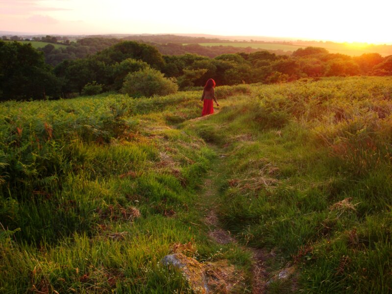 Person walking on a hill at sunset