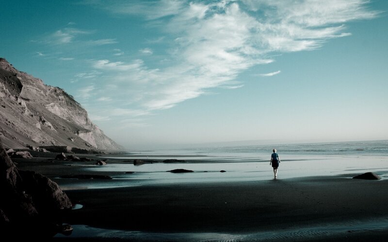 Person walking on beach at dusk
