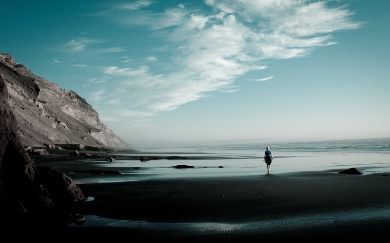 Person walking on beach at dusk