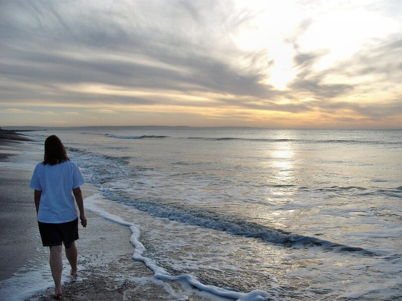 Person walking on beach at sunset