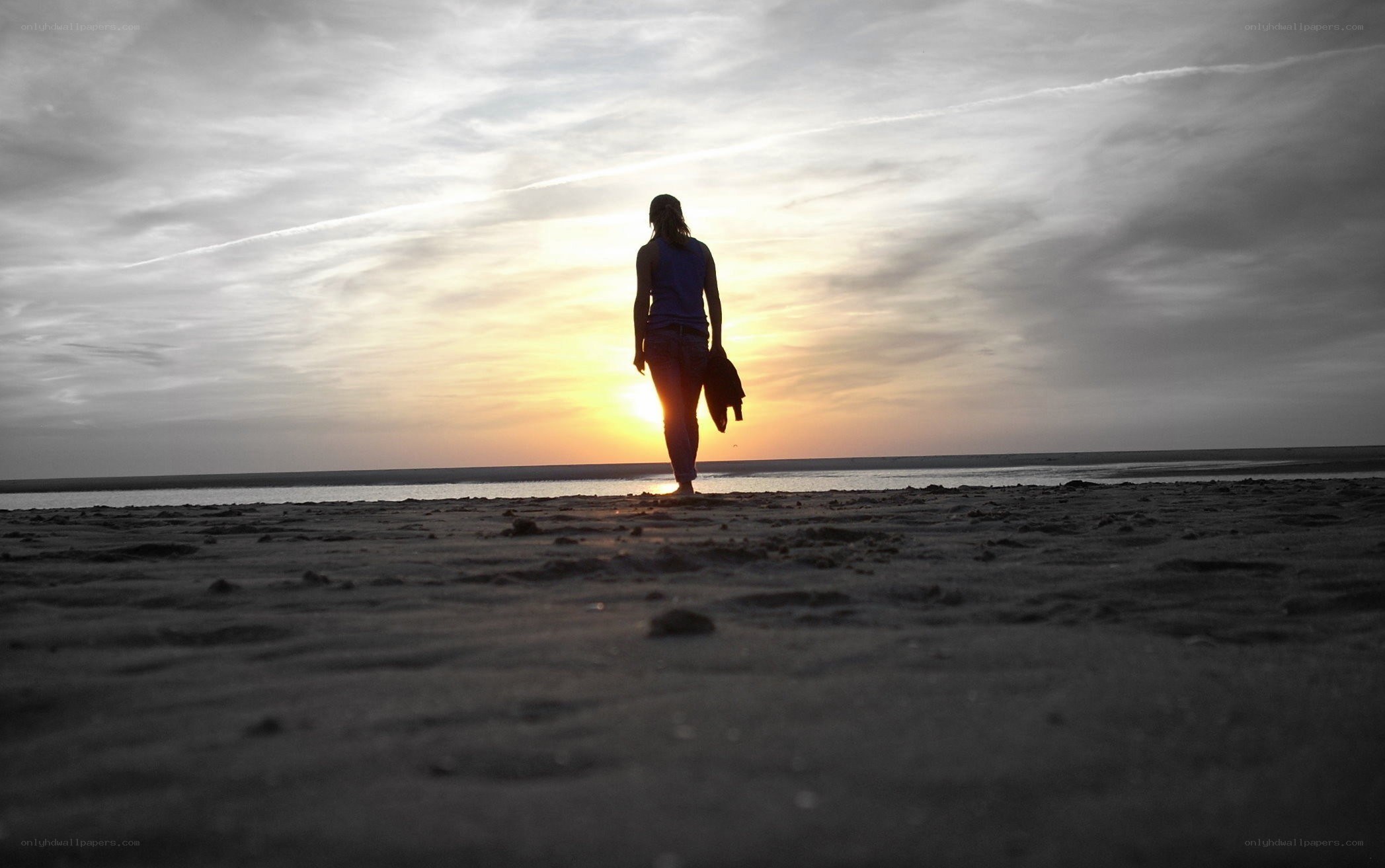 person walking on beach at sunset