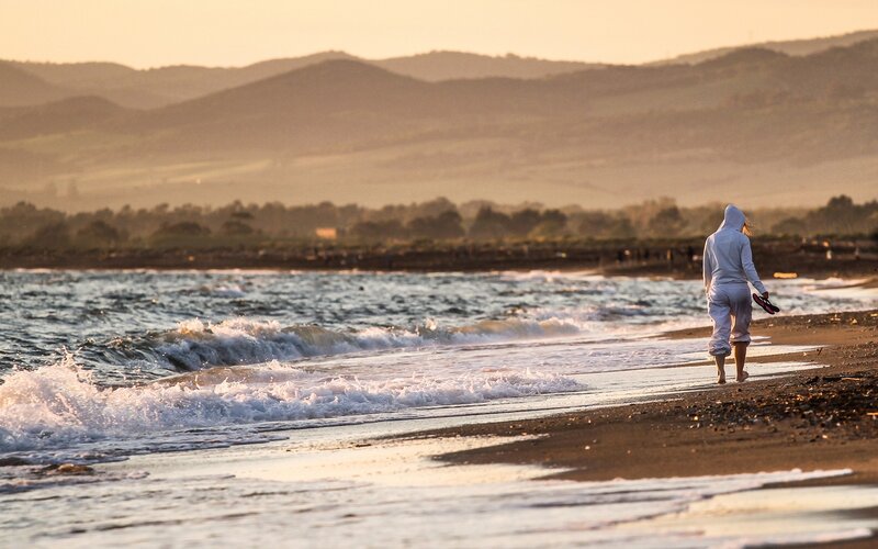 Person walking on beach at sunset