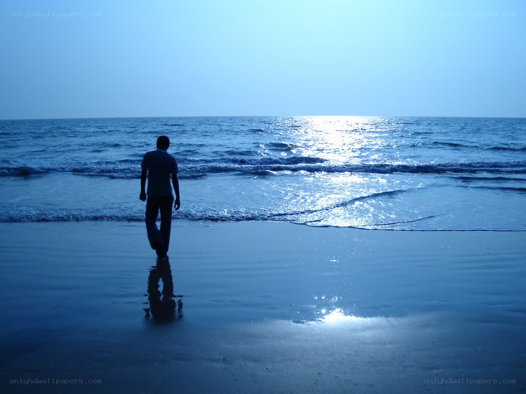 Person walking on beach at sunset