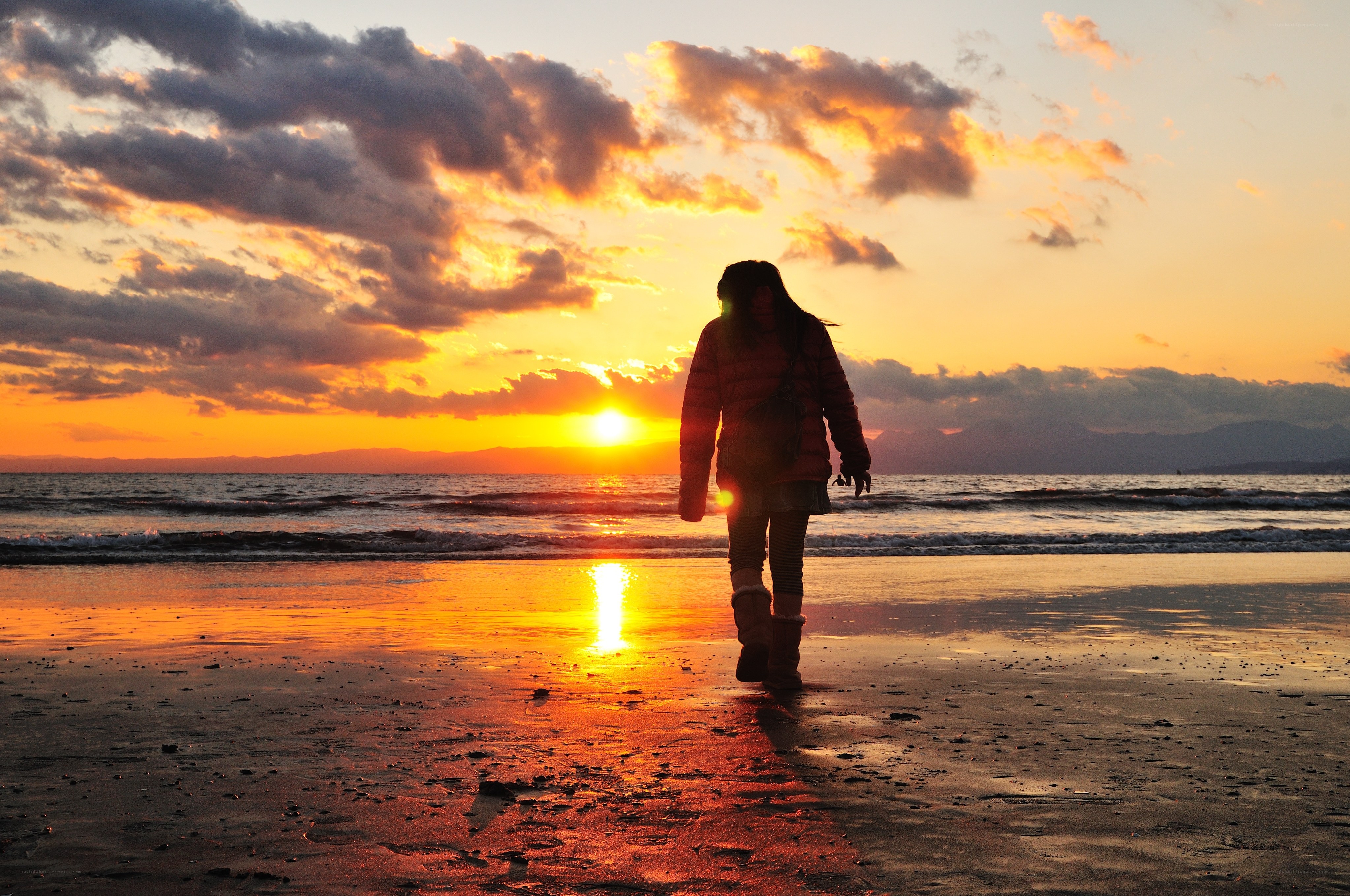 Person walking on beach at sunset