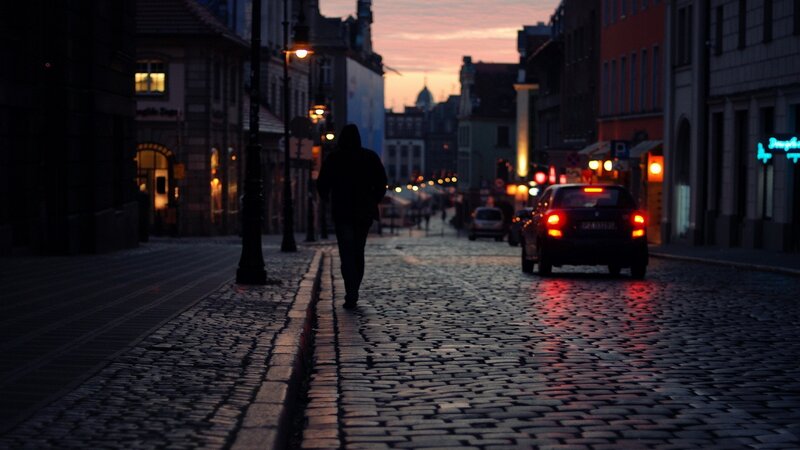 Person Walking on Cobblestone — Dark Blue