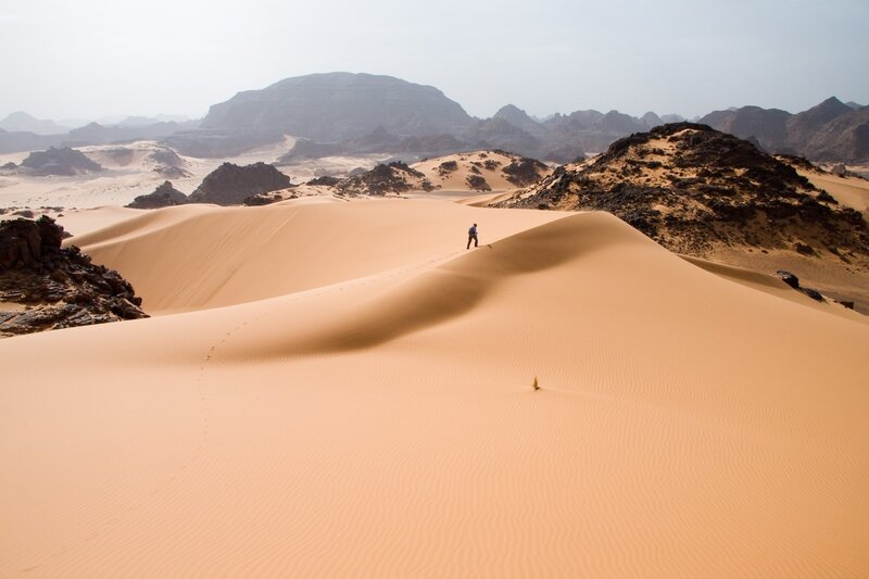 Person Walking on Sand Dune — Orange