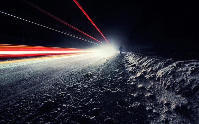 Person walking on snowy road at night