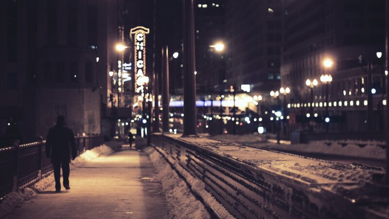 Person walking on snowy sidewalk at night