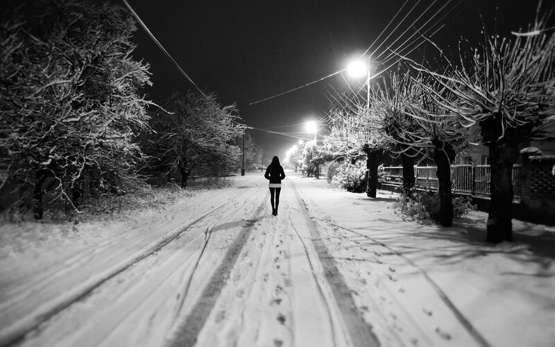 Person walking on snowy street at night