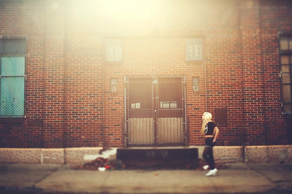 person walking past brick building