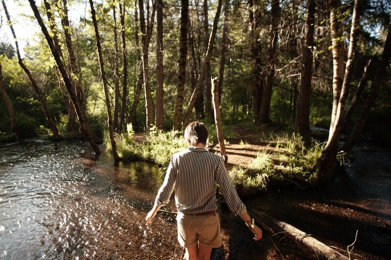 Person walking through forest stream