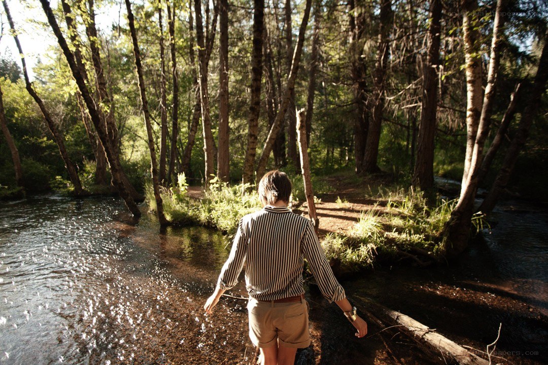 Person walking through forest stream